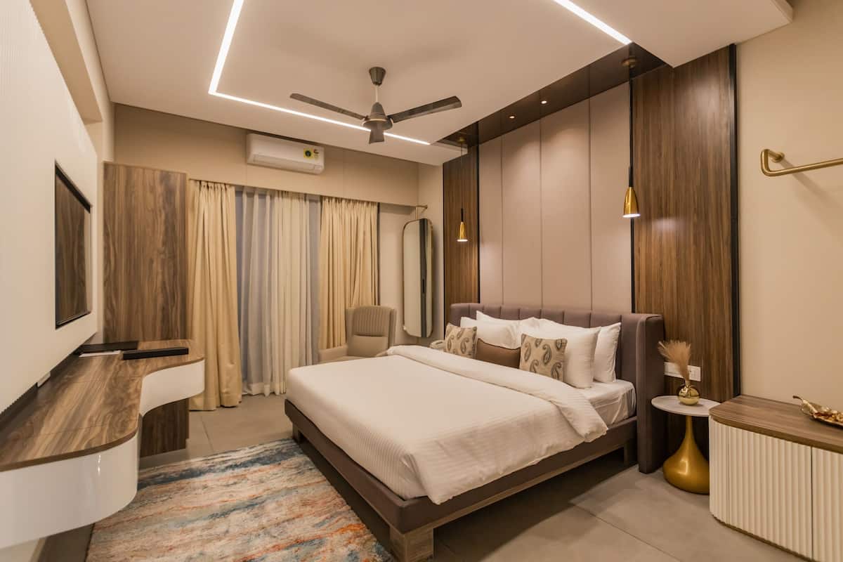 A modern bedroom with a large bed, a ceiling fan, a bedside table, and a small round table with a lamp.