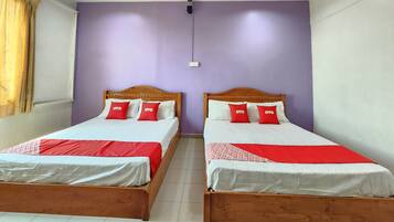 Two wooden beds with white and red bedding, a purple wall, and a window with curtains.