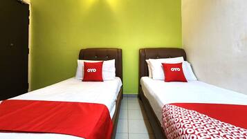 Dos camas individuales con ropa de cama roja y blanca, una pared verde y una lámpara sobre las camas.