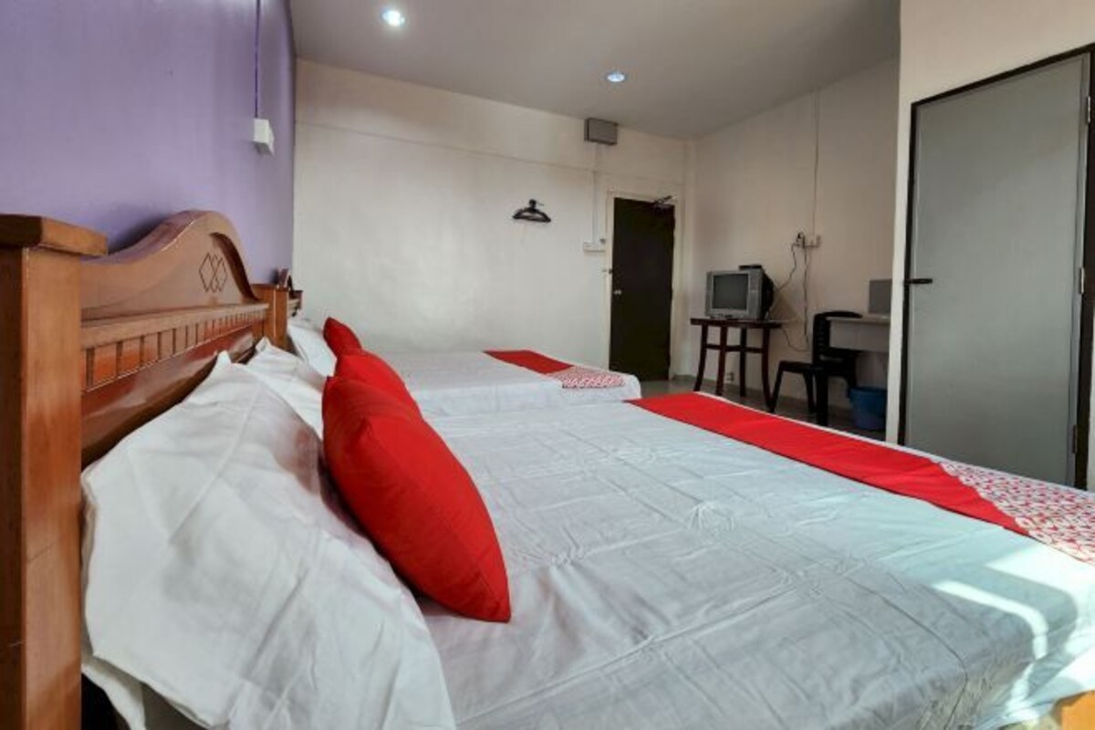 A hotel room with two beds, a television, and a desk.