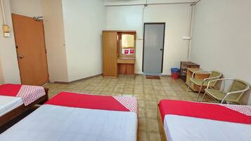 A room with three beds, a wooden wardrobe, a small desk, and a mirror.