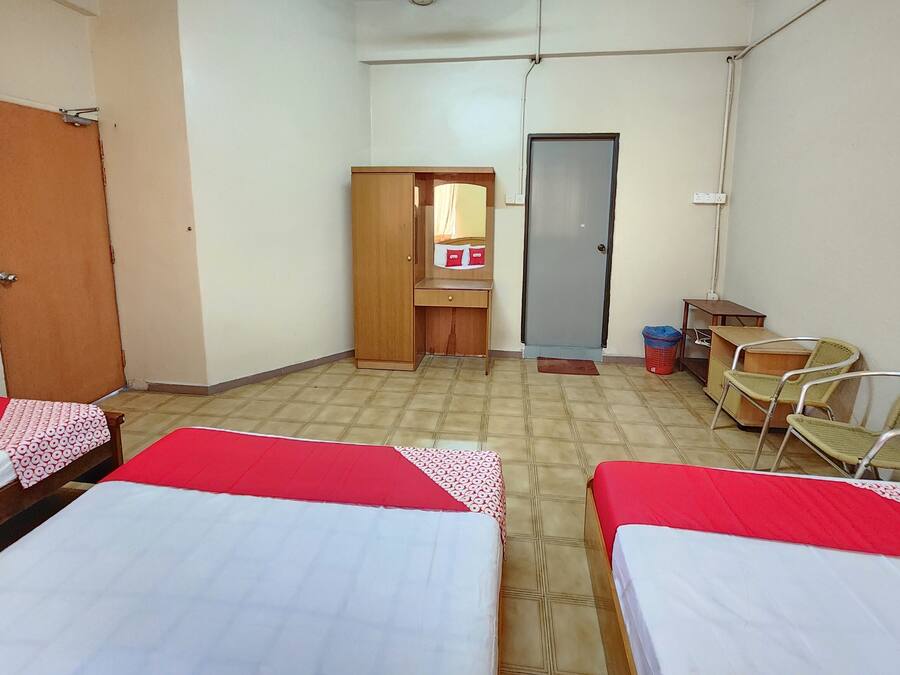 A room with three beds, a wooden wardrobe, a small desk, and a mirror.