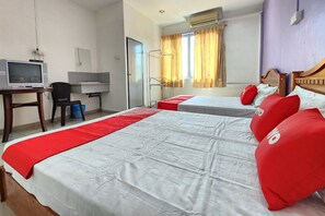 Quarto de hotel com duas camas, uma escrivaninha com computador e uma janela com cortinas.