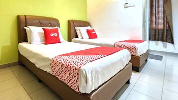 Dos camas con cabeceros marrones, ropa de cama blanca y almohadas rojas.