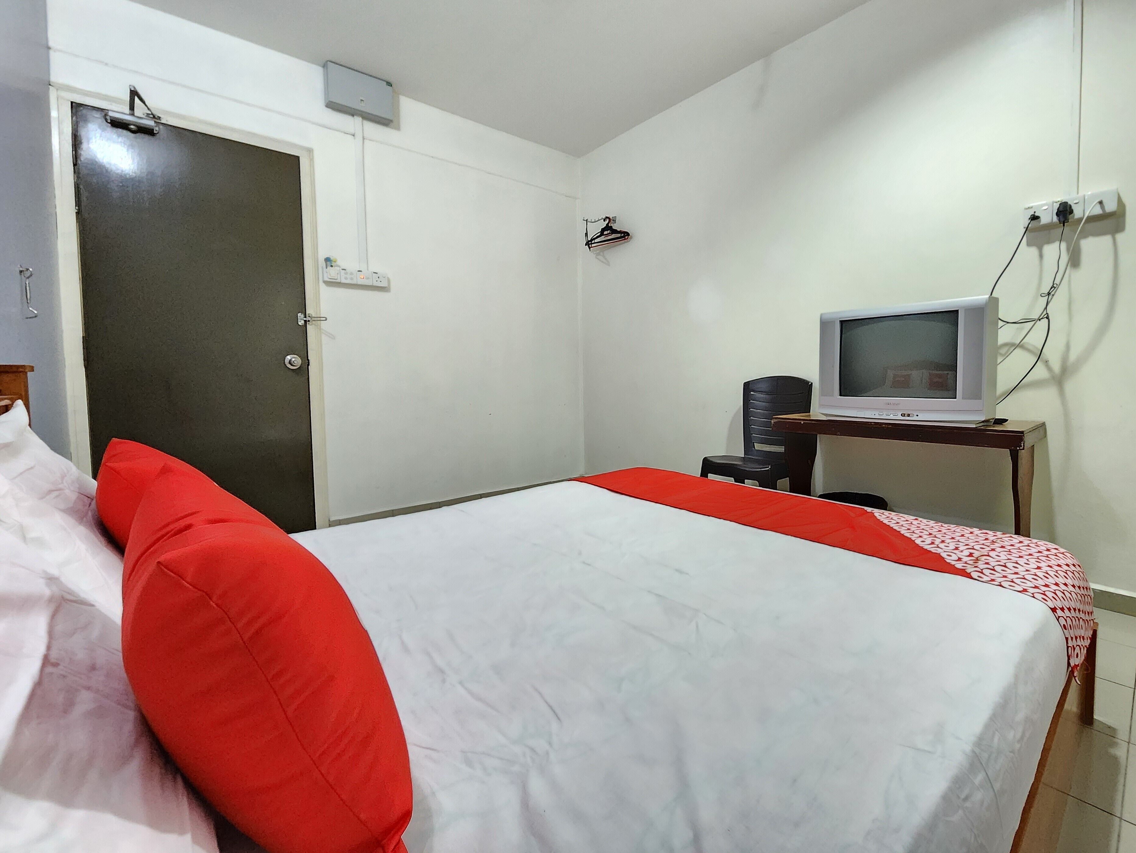 Una habitación de hotel con una cama, un televisor sobre un escritorio y una puerta.
