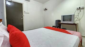 Una habitación de hotel con una cama, un televisor sobre un escritorio y una puerta.
