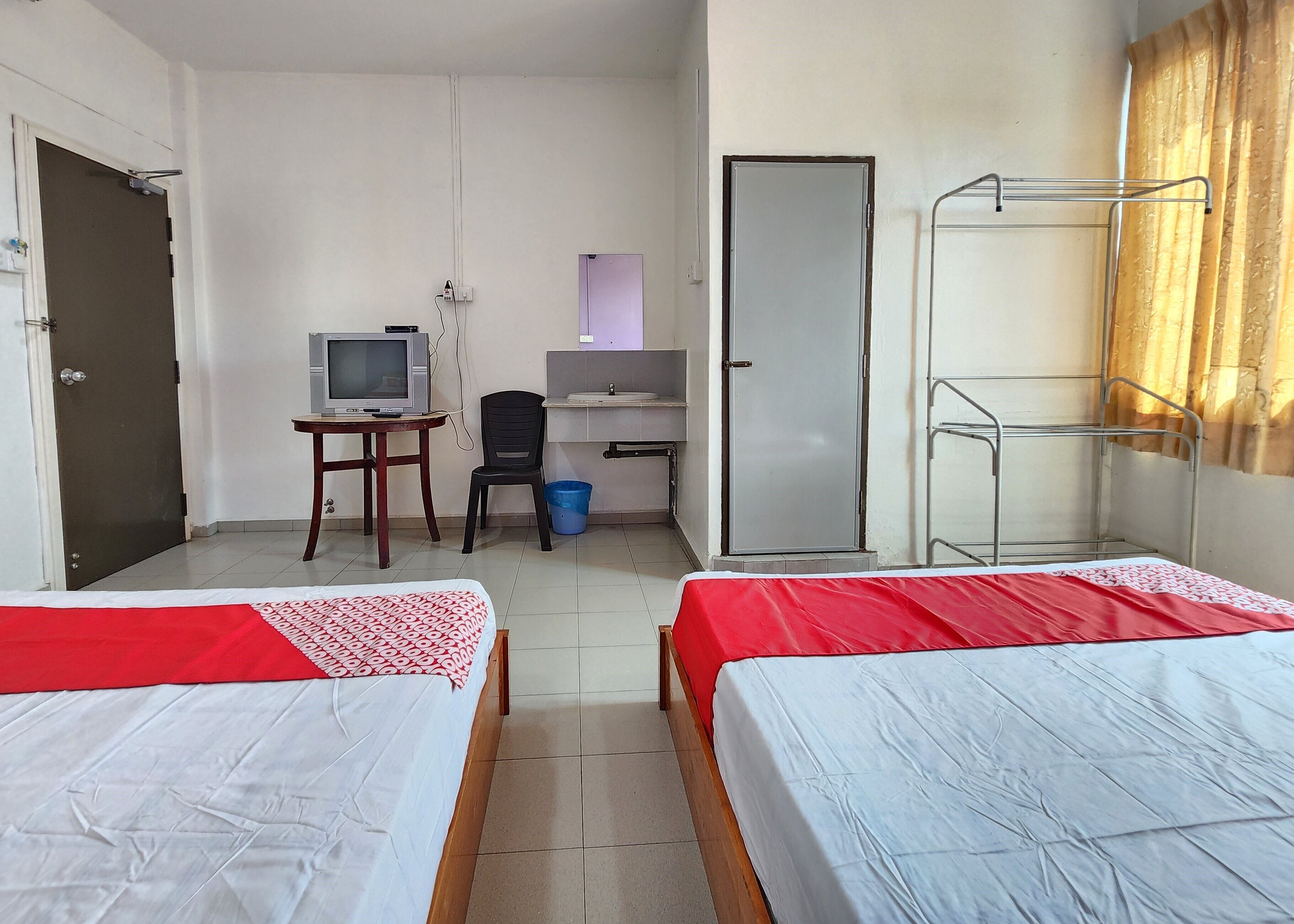 A hotel room with two beds, a desk with a computer, a TV, and a wardrobe.