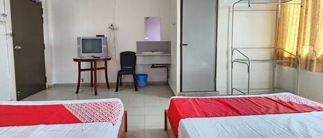A hotel room with two beds, a desk with a computer, a TV, and a wardrobe.
