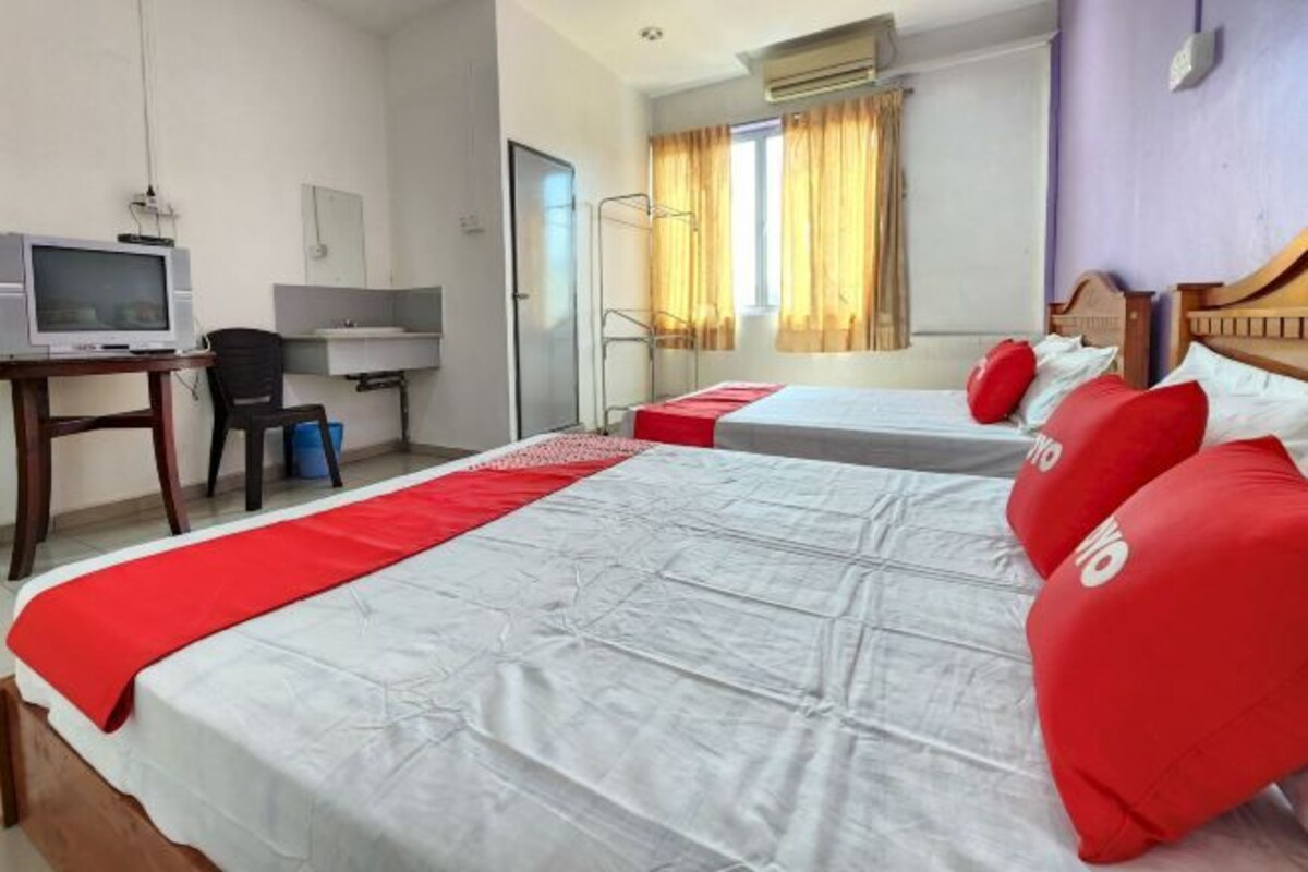 A hotel room with two beds, a desk with a computer, a chair, and a window with curtains.