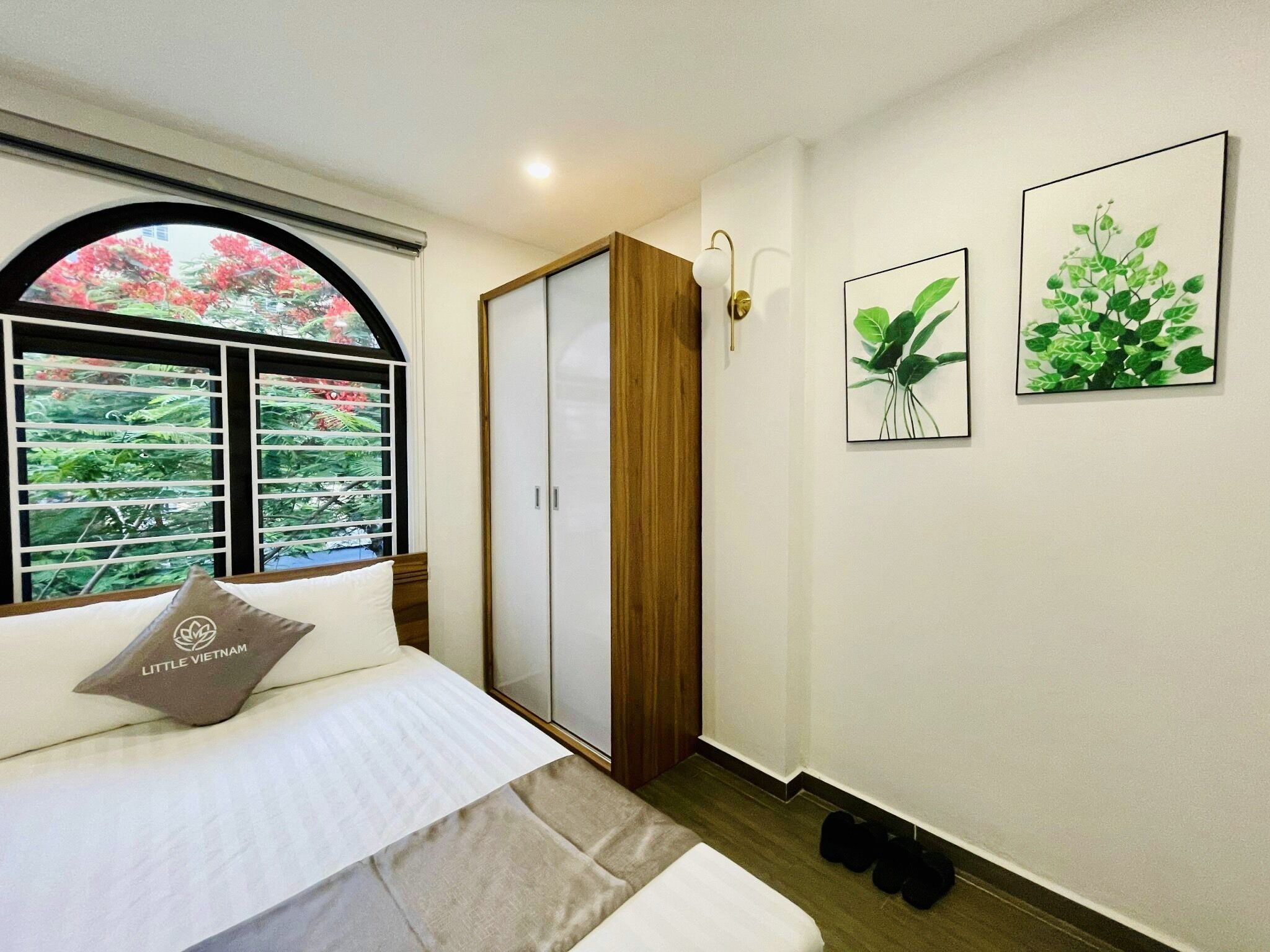 Un dormitorio con cama, armario, ventana con persianas y dos cuadros en la pared.