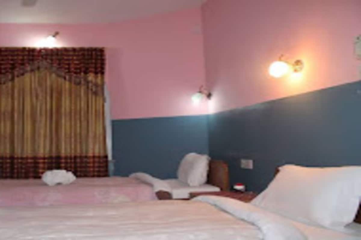 A hotel room with a bed, a chair, a desk, and a curtain.
