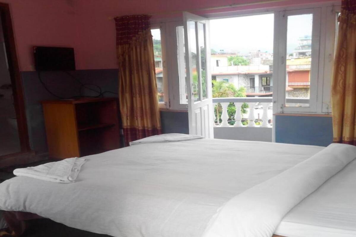A bedroom with a bed, a desk, and a window with curtains.