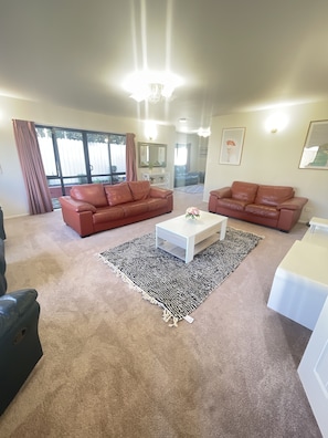 A living room with two leather sofas, a white coffee table, and a black and white rug.