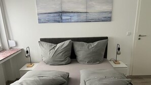 Et soveværelse med en seng, to sengeborde, et natbord, en lampe, et billede og en dør.
