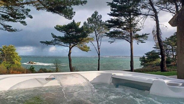 Un jacuzzi con vistas al océano y a los árboles.
