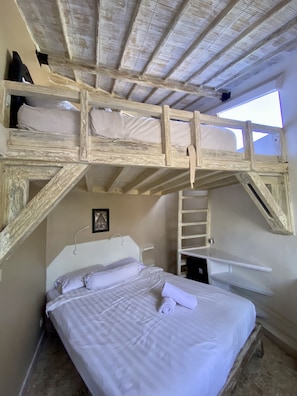 A room with a bunk bed, a white headboard, a ladder, and a small shelf.