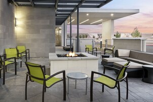 An outdoor patio area with seating, a fire feature, and a view of the cityscape.