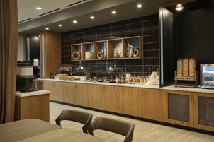 A modern kitchen with wooden cabinets, a central island, and a black backsplash.