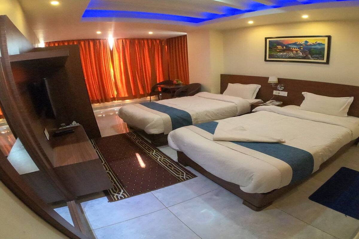 Habitación de hotel con dos camas, televisión, escritorio y un cuadro en la pared.