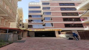 Un edificio de varios pisos con un letrero que dice "Hotel Tara Suites" y una persona de pie cerca de una puerta.