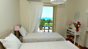 A bedroom with two beds, a desk, a chair, and a balcony with a view of the sea. - Citron Pale Villa with Private Pool (Trifylia)