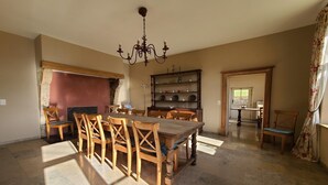 A dining area with a wooden table and chairs, a chandelier, and a bookshelf. - Accommodation in the forges of Orval (Orval)