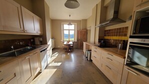 A kitchen with wooden cabinets, a dining table, and a view of the outdoors. - Accommodation in the forges of Orval (Orval)