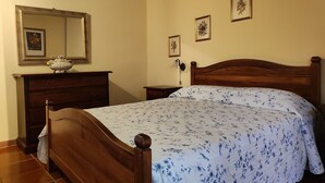 Un dormitorio con cama de madera, cómoda y espejo.