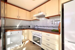 A compact kitchen with a dishwasher, oven, microwave, and a sink.