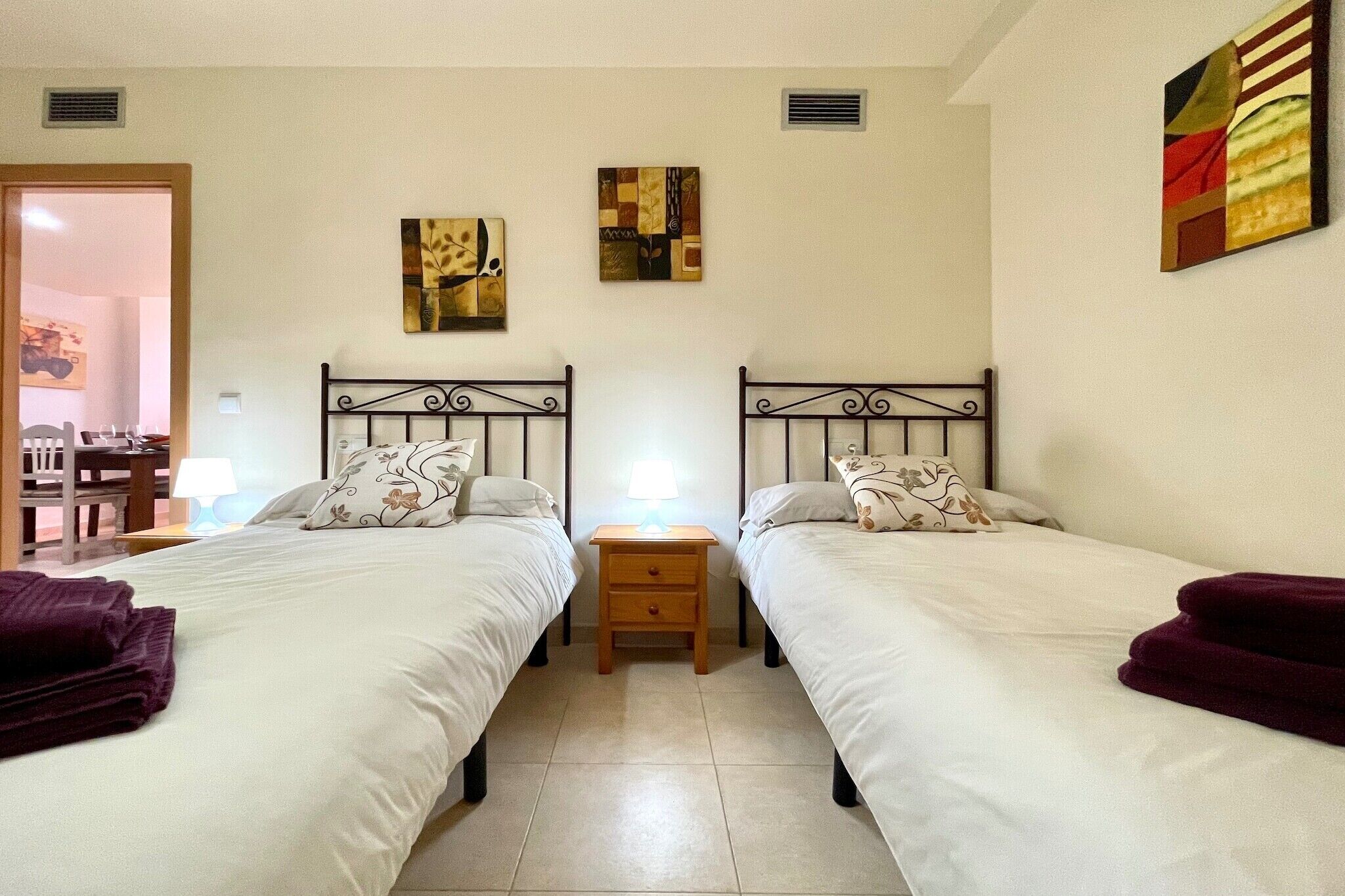Habitació doble amb dos llits, una tauleta de nit i obra d'art a les parets.