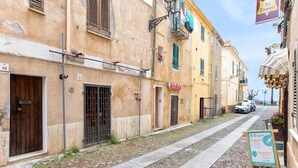 A narrow street with buildings, a sign for 'Al Turgi', and a parked car.