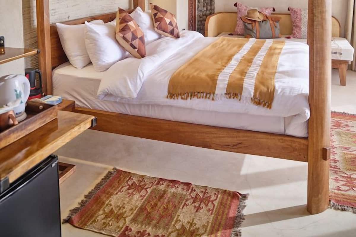Un dormitorio con una cama de madera, un ventilador de techo y un diseño rústico en la pared.