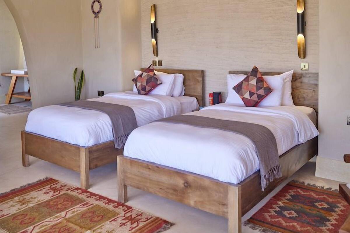 Una habitación con dos camas de madera, un ventilador de techo y apliques decorativos en las paredes.
