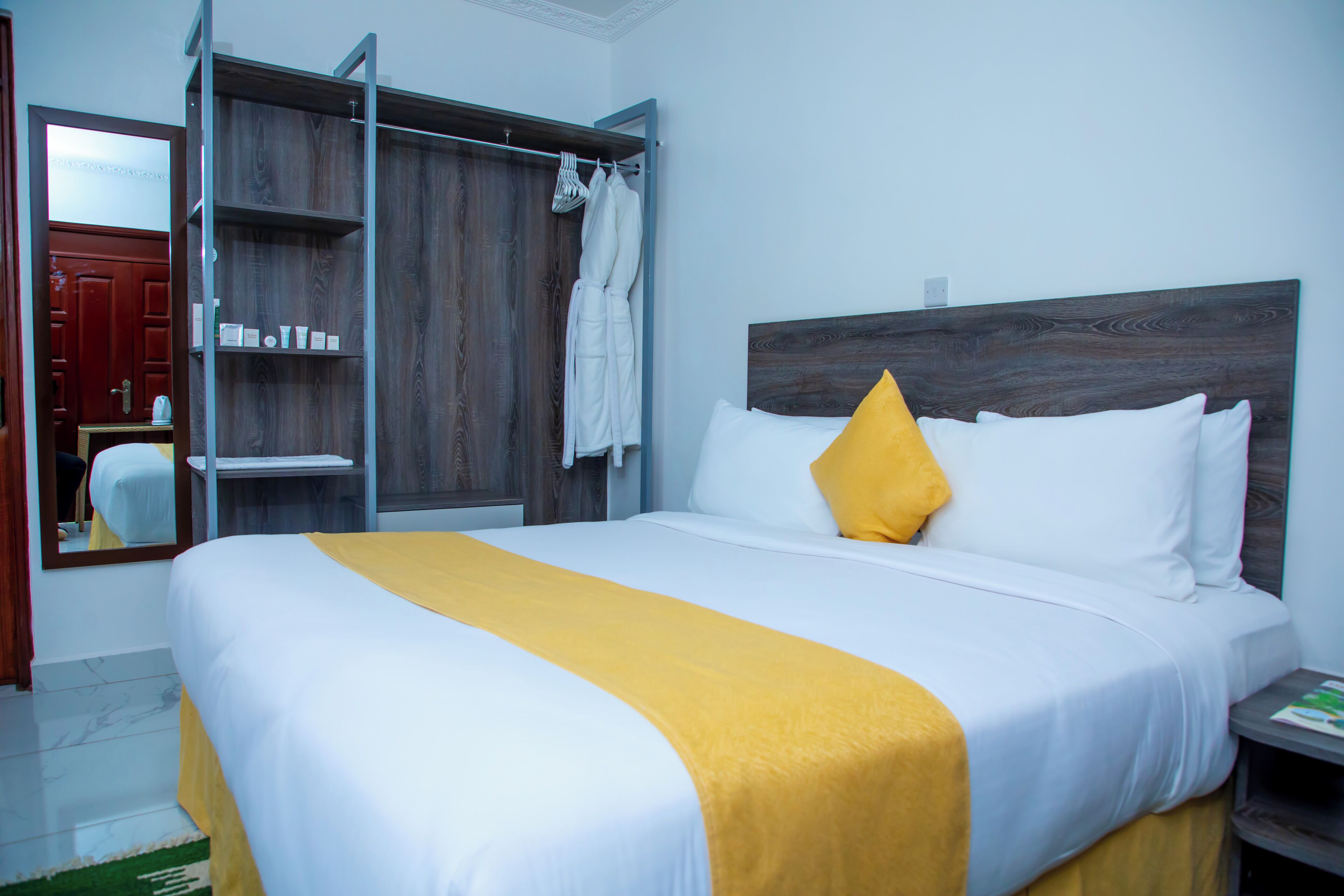 Une chambre d’hôtel avec un lit, une armoire et un miroir.