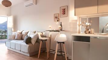A modern living room with a sofa, a dining area, and a kitchen.