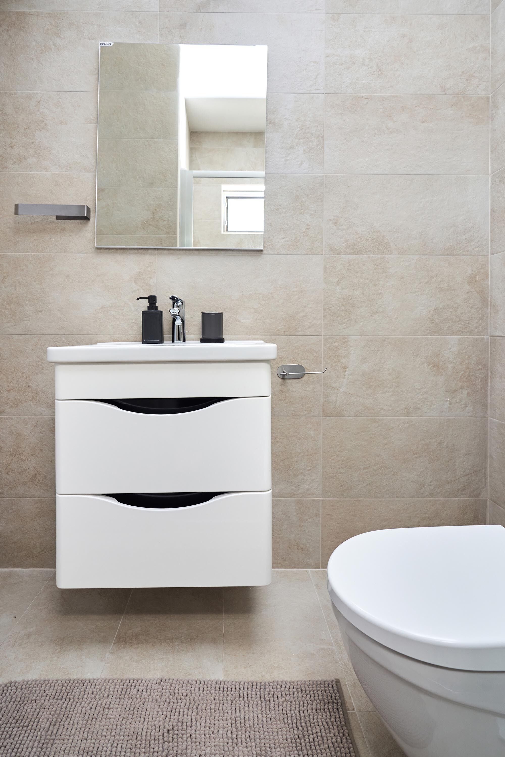 Un bany modern amb un lavabo blanc, un mirall i un vàter.