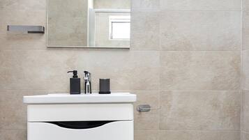 Un bany modern amb un lavabo blanc, un mirall i un vàter.