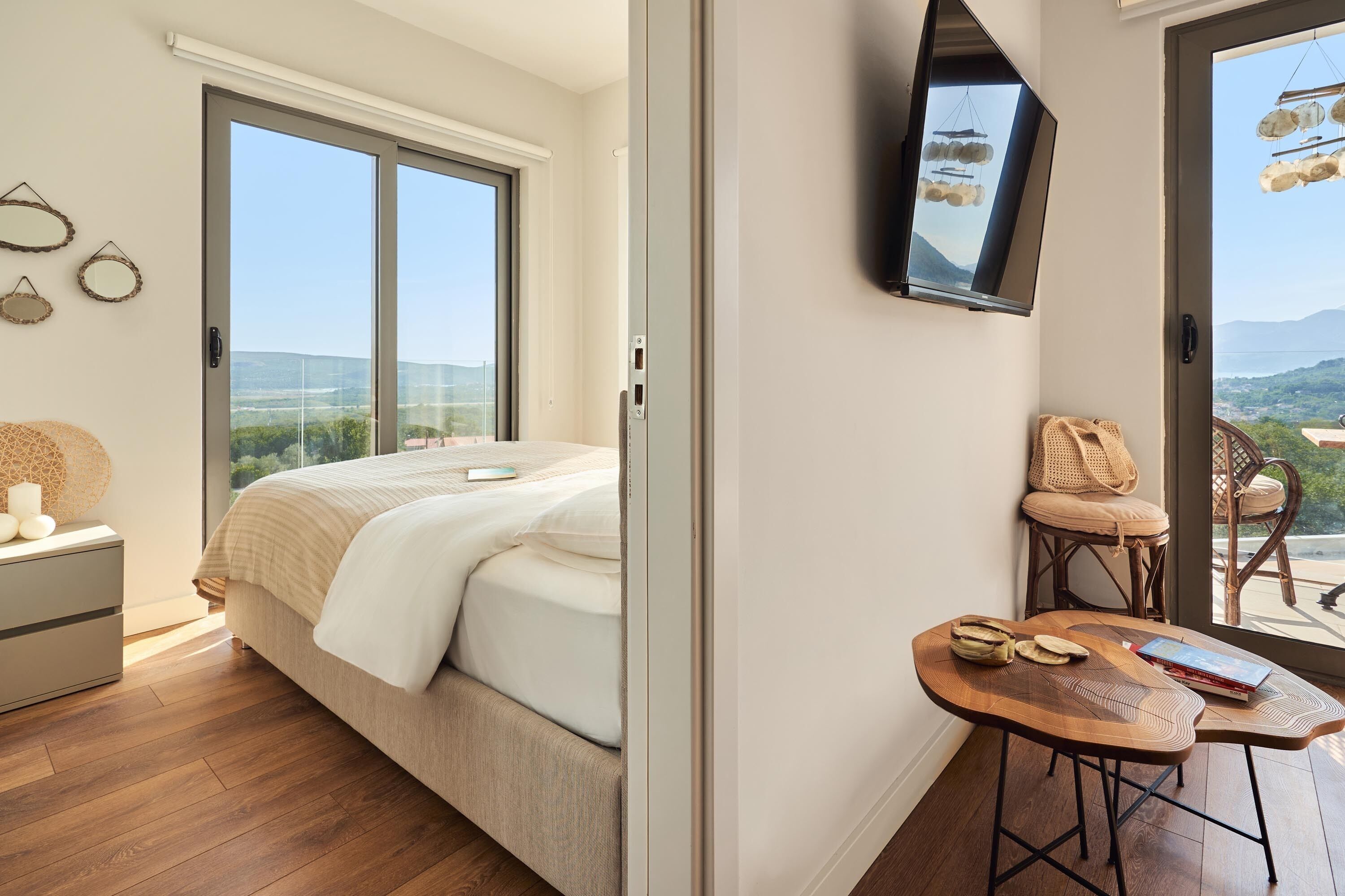 Ein Schlafzimmer mit einem Bett, einem Schreibtisch und einem Sessel. Ein Fenster bietet einen Blick ins Freie.