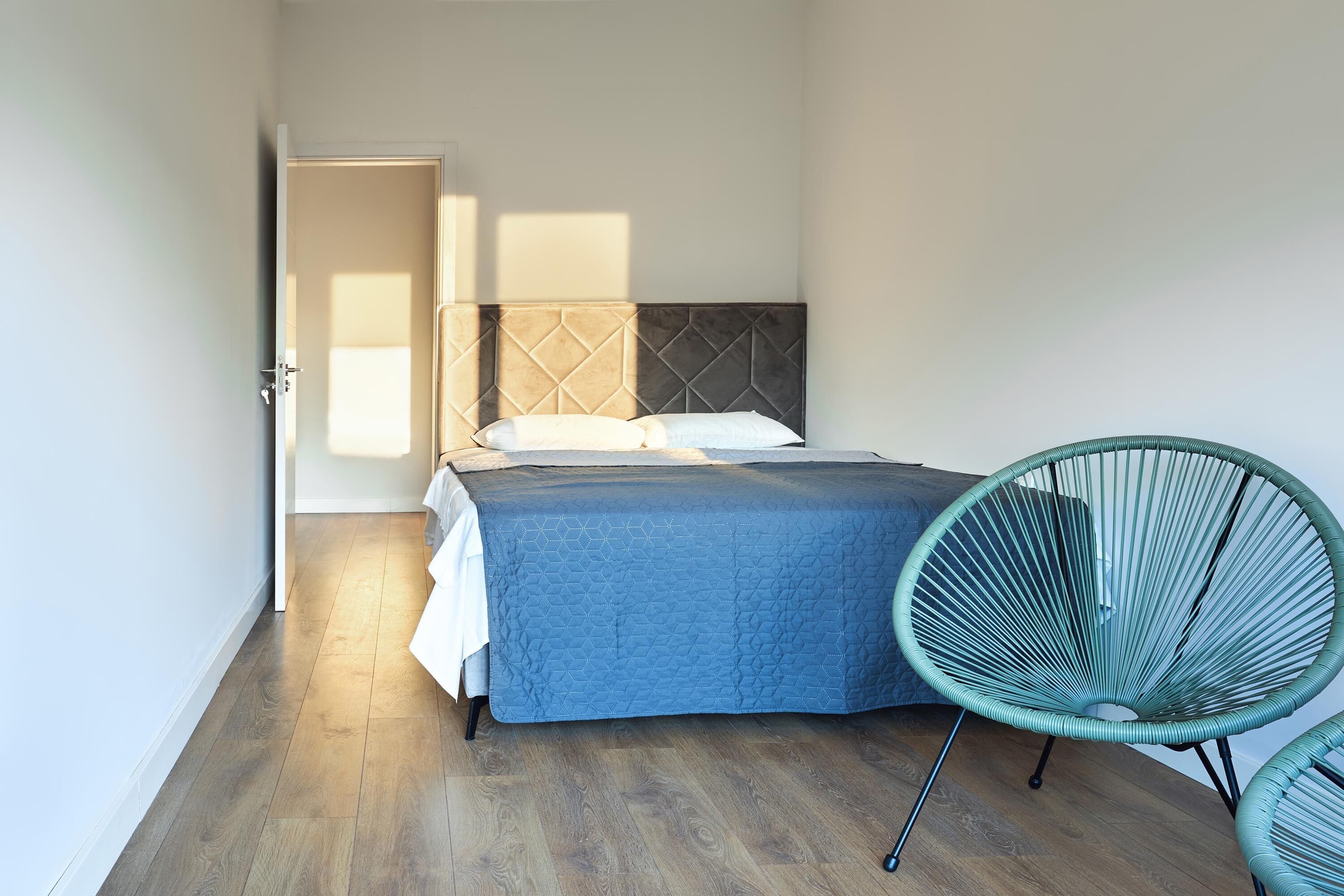 A bedroom with a bed, a chair, and a door.
