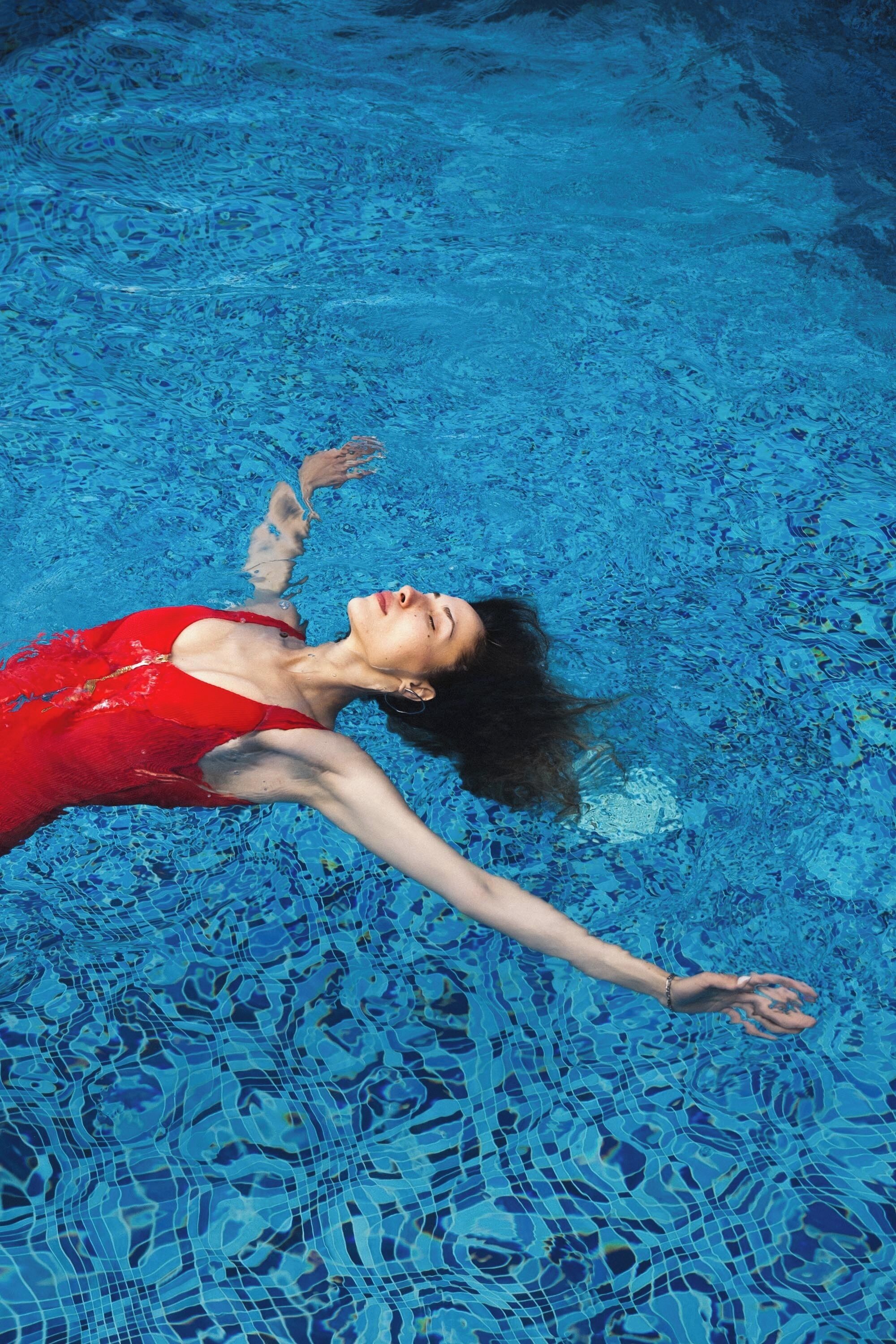 Uma pessoa flutuando em uma piscina azul.