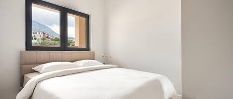 A bedroom with a bed, a window, and a view of buildings.