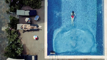An aerial view of a swimming pool with two lounge chairs and a beach ball on the deck.