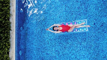 Una persona recostada en una colchoneta flotante en una piscina.