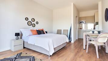 A modern bedroom with a bed, bedside tables, a desk, and a chair.