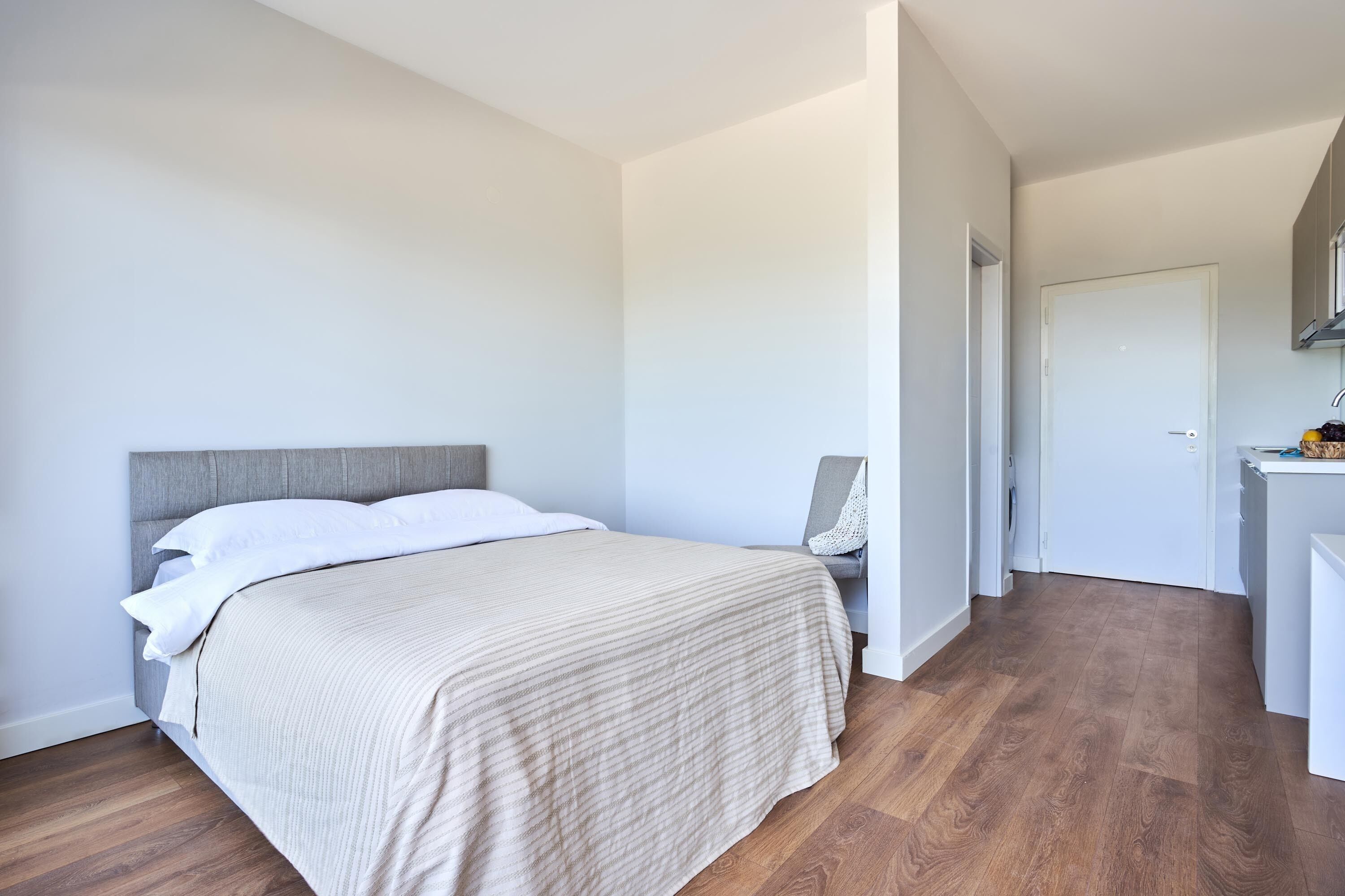 A bedroom with a bed, a chair, and a desk.