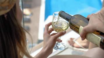 Una persona sirve vino en una copa cerca de una piscina.
