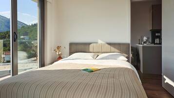 Una habitación de hotel moderna con una cama grande, vistas al exterior y una zona de kitchenette.