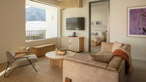 A modern living room with a sofa, a coffee table, a TV, and a large window with a mountain view. - Drift Palm Springs (PALM SPRINGS)