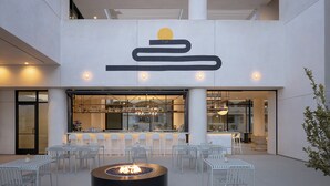 An outdoor seating area with a fire pit, white chairs, and a bar with a modern design. - Drift Palm Springs (PALM SPRINGS)