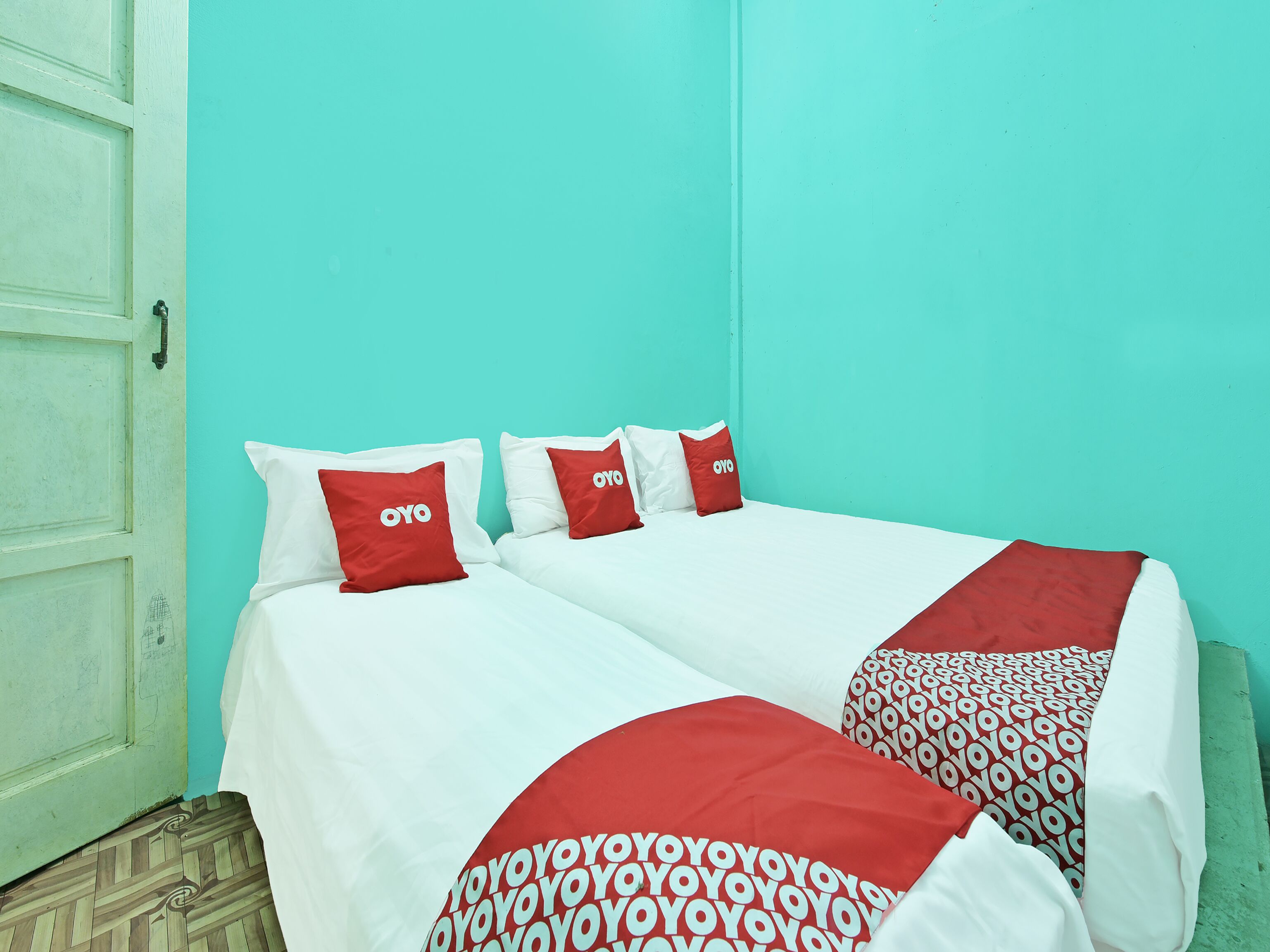 A room with two beds, each with white bedding and red pillows with the 'OYO' logo.